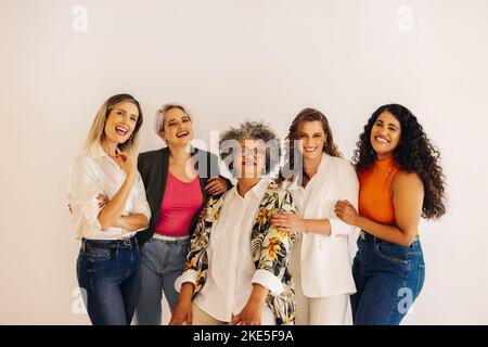 Diverse female entrepreneurs smiling at the camera while standing together in an office. Group of multicultural businesswomen working as a team in a s Stock Photo