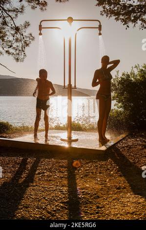 Young couple, boy and girl, standing washing and outdoor shower, summer time, Croatia Stock Photo