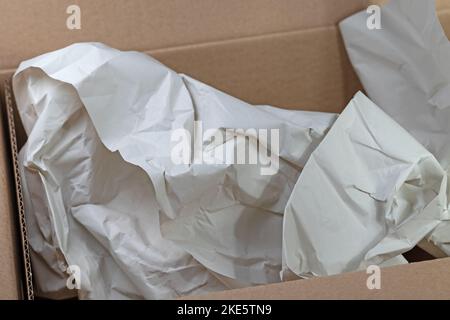 Empty cardboard box with crumpled wrapping paper Stock Photo