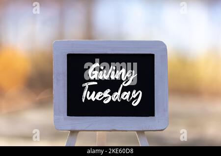 Giving Tuesday text message on chalkboard easel soft bokeh background copy space Stock Photo
