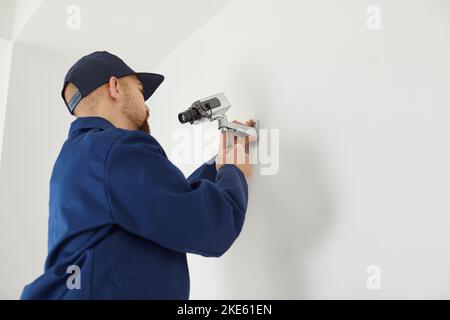Man technician mount surveillance camera on wall Stock Photo