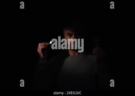 man with electric bulb and lit match looking at camera isolated on black Stock Photo