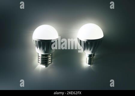 Two luminous LED lamps with different bases on a light background. Energy saving technology. Stock Photo