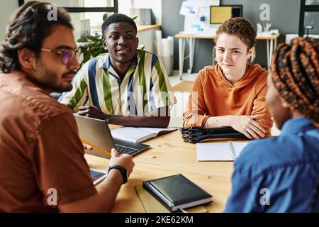 Young creative designer with myoelectric arm and African American man listening to their colleague during discussion of new ideas Stock Photo