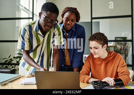 Young African American employee pointing at laptop screen while explaining two intercultural female colleagues information Stock Photo