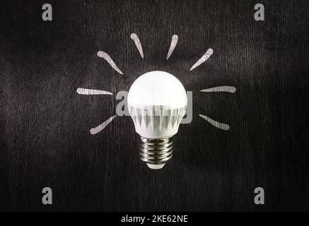 LED lamp on a dark wooden background. Energy-saving technology. Stock Photo