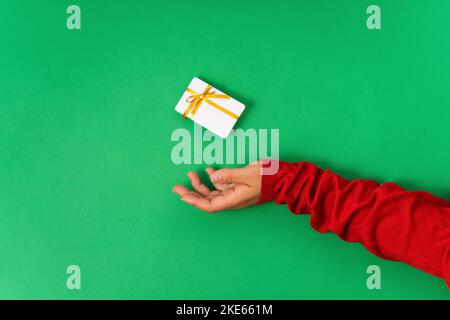 Female hand holding levitating bonus card template mockup, bank credit card with gift ribbon for online shopping isolated on green background Stock Photo