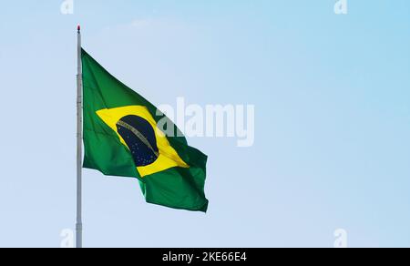 Brazilian flag waving in a beautiful clear sky, with the sunlight lighting up the flag. Brazil flag on the left with space for text on the right. Stock Photo