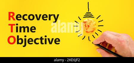 RTO recovery time objective symbol. Concept words RTO recovery time objective on a beautiful yellow background. Businessman hand. Light bulb. Business Stock Photo