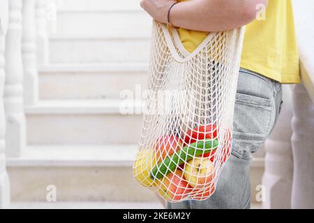 Faceless Woman With Cotton Mesh Shopper Bag Or Eco String Bag Coming Home From Farmers Market. Stock Photo