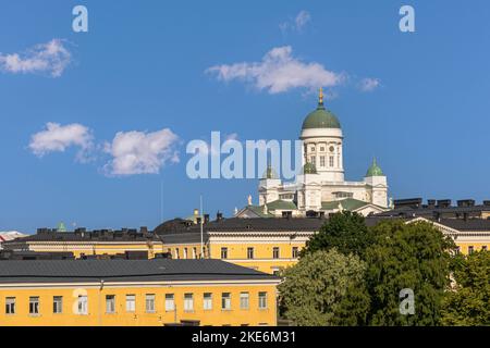 Helsinki, Finland - July 20, 2022: The white Cathedral with green domes towers over yellow cityscape facade under blue cloudscape Stock Photo