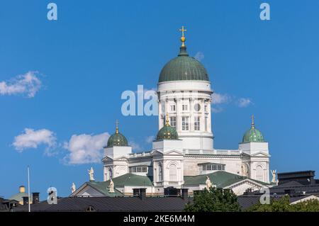 Helsinki, Finland - July 20, 2022: The white Cathedral with green domes towers over black cityscape roofs under blue cloudscape Stock Photo