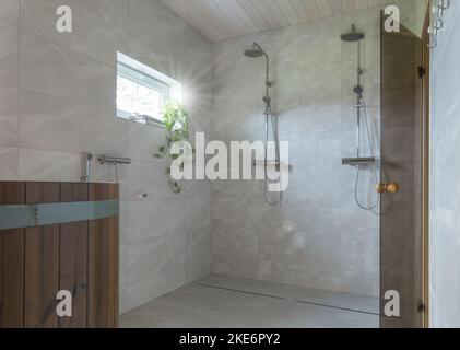 Modern bathroom with wooden sauna, open showers and marble walls and floors. Stock Photo