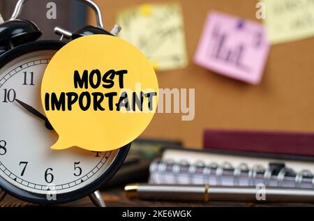 Business concept. The alarm clocks have a sticker with the inscription - Most Important. There are office items in the background in a blurry backgrou Stock Photo