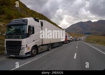Kazbegi, Georgia - October 3, 2022: Several kilometres long line of Trucks by the side of the Georgian military highway near Kazbegi waiting for cross Stock Photo