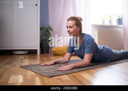 Sporty fit yogini woman practices yoga asana bhujangasana, cobra pose  Stock Photo