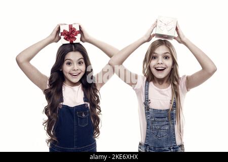 Learned how to gift wrap. Happy little girls holding gift boxes over head. Small children with gift packs on boxing day. Adorable kids with beautifull Stock Photo