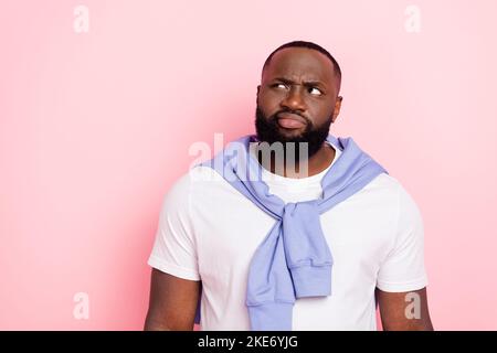Photo of grumpy young male look blank space brainstorming can't decide choose isolated on pink color background Stock Photo