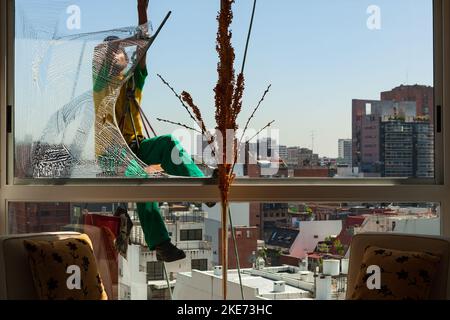 A window washer cleans our apartment windows on the 11th floor in Buenos Aires. Stock Photo