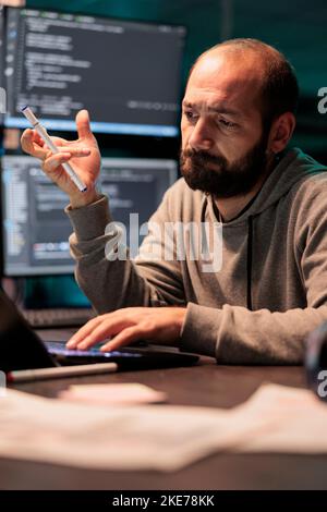 App developer brainstorming ideas about coding solution, finding algorithm to create database script. Feeling pensive and thinking about software developing system late at night. Stock Photo