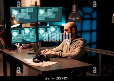 Hacker programmer hacking system at office, using virus to produce computer malware and server error. Data thief stealing information from company software app, working with multiple monitors. Stock Photo