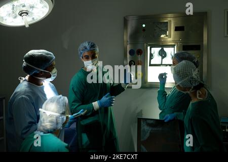 Diverse group of surgeons in discussing x-rays in operating theatre before operation Stock Photo