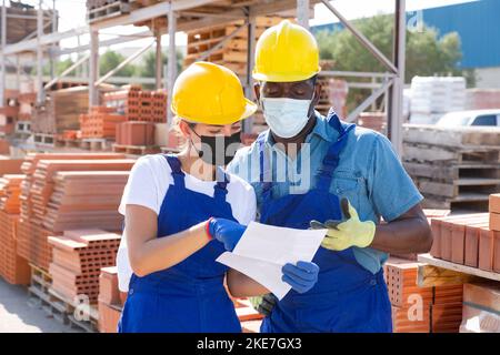 Two workers in masks keep track of the number of redbricks Stock Photo