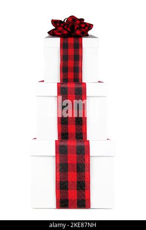 Stacked white Christmas gift boxes with red and black buffalo plaid bow and ribbon. Side view isolated on a white background. Stock Photo