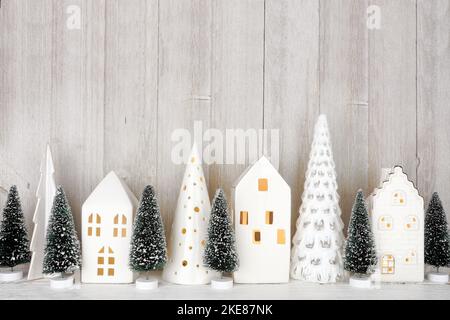 Modern Christmas tree decor and white houses on a shelf against a rustic grey wall background Stock Photo