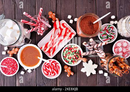 Christmas hot chocolate bar with a mixture of sweet toppings. Top view table scene on a dark wood background. Stock Photo