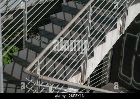 staircase architecture: detail of the external stairs with concrete steps and the railing and handrail and in white painted steel. Stock Photo