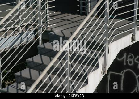 staircase architecture: detail of the external stairs with concrete steps and the railing and handrail and in white painted steel. Stock Photo