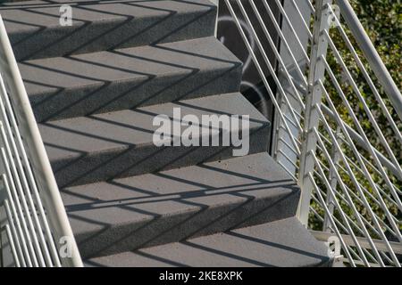 staircase architecture: detail of the external stairs with concrete steps and the railing and handrail and in white painted steel. Stock Photo