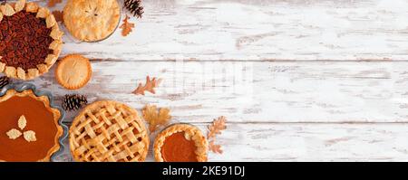 Selection of homemade autumn pies. Pumpkin, apple and pecan. Above view corner border on a white wood background with copy space. Stock Photo