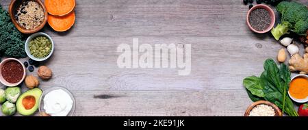 Healthy food ingredients. Top view double side border on a wood banner background. Copy space. Super food concept with green vegetables, berries, whol Stock Photo