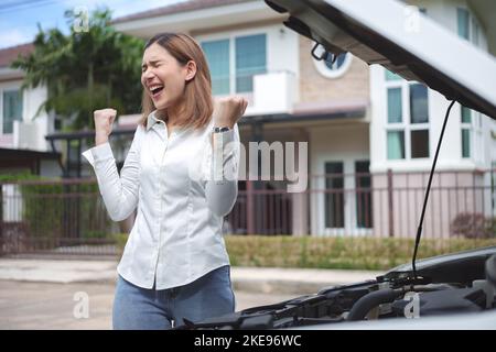 Young upset woman standing near the broken car with opened hood. Stock Photo