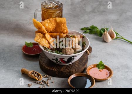 Bakso or indonesian meatball served with broth soup, tofu, noodle and deep fried wonton or dumpling on white bowl Stock Photo