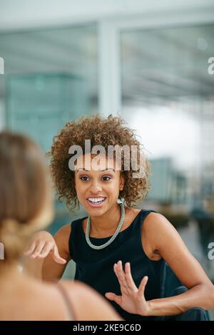 Catching up on office gossip. two smiling coworkers talking together while sitting in a modern office. Stock Photo