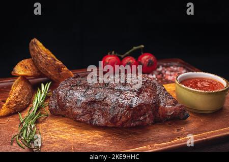 Meat steak with fried potatoes, sauce, and baked tomatoes Stock Photo