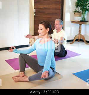 Relaxing mind, body and soul. a yoga instructor guiding a senior man in a yoga class. Stock Photo