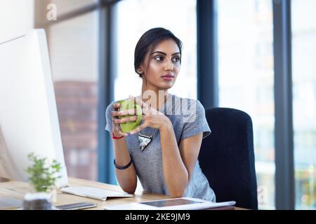 Thinking about the workday ahead of her. a thoughtful young businesswoman having a coffee break at her desk. Stock Photo