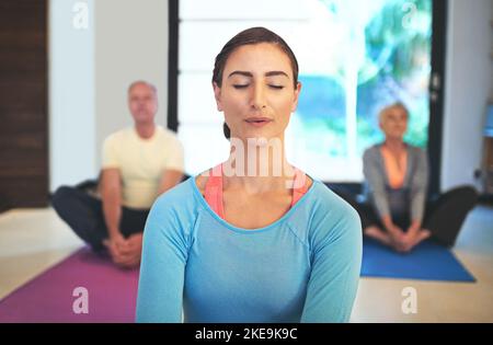 Inhale deeply, exhale slowly. a yoga instructor guiding a senior couple in a yoga class. Stock Photo
