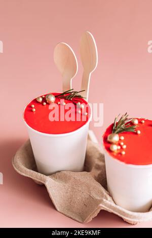 Takeaway Christmas cake in white disposable cups on a stand against a pink background Stock Photo