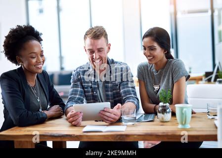 Lots of creative input here. a team of young colleagues using a digital tablet together at work. Stock Photo