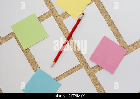 Colorful sticky notes on a cork board with blank white post card with pencil Stock Photo