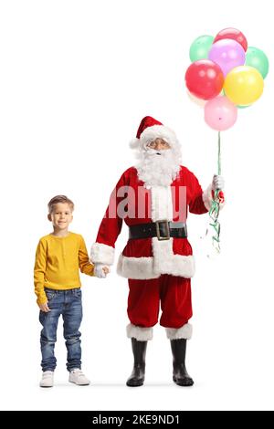 Full length portrait of santa claus with a bunch of balloons holding hands with a little boy isolated on white background Stock Photo
