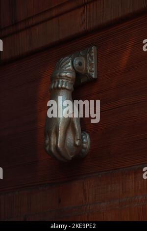 Old Brass Doorknocker with Hand Shape on Old Wooden Door in Alcudia Spain Stock Photo