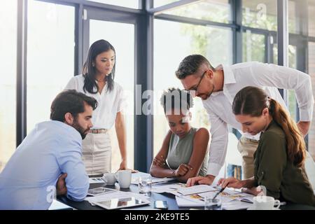 All that creative thinking has made them hungry. a group of diverse businesspeople having a meeting in the boardroom. Stock Photo
