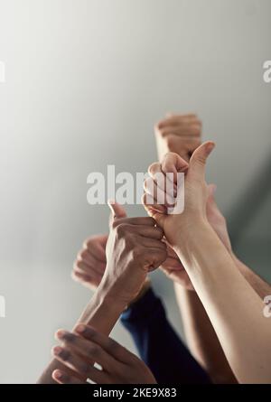 Exceptional achievements are within our reach. a group of office workers giving thumbs up together. Stock Photo