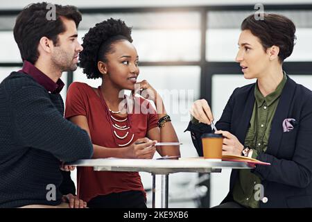 When hard work meets focus, success is guaranteed. a group of businesspeople meeting around a small table in their office. Stock Photo